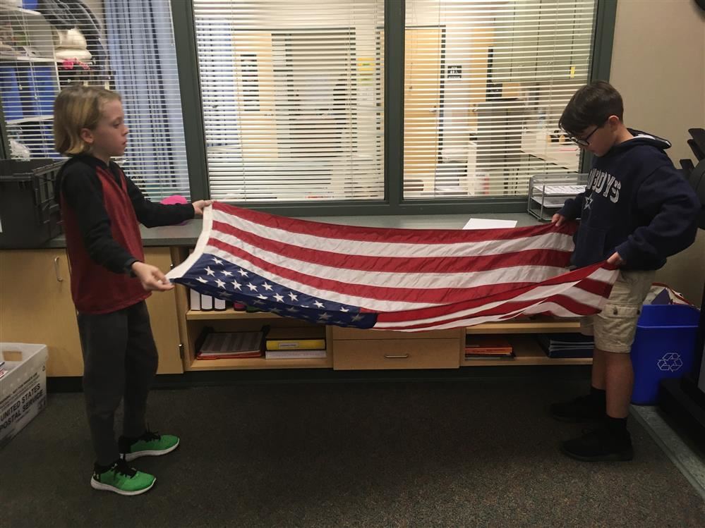 Two students folding an American flag.